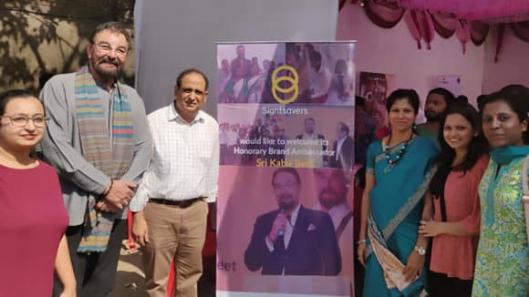 Six people stand next to a banner that welcome Sightsavers' Honorary Brand Ambassador.