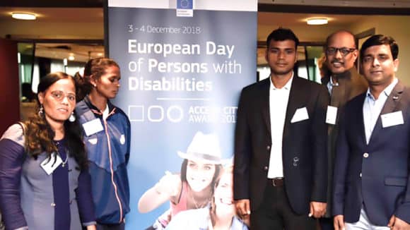 People stand in front of a sign that says: European Day of Persons with Disabilities.