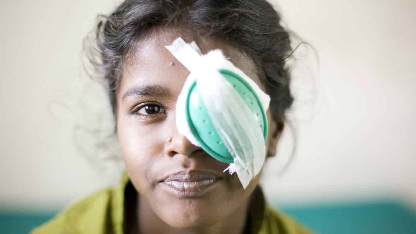 A girl with an eye patch smiling.