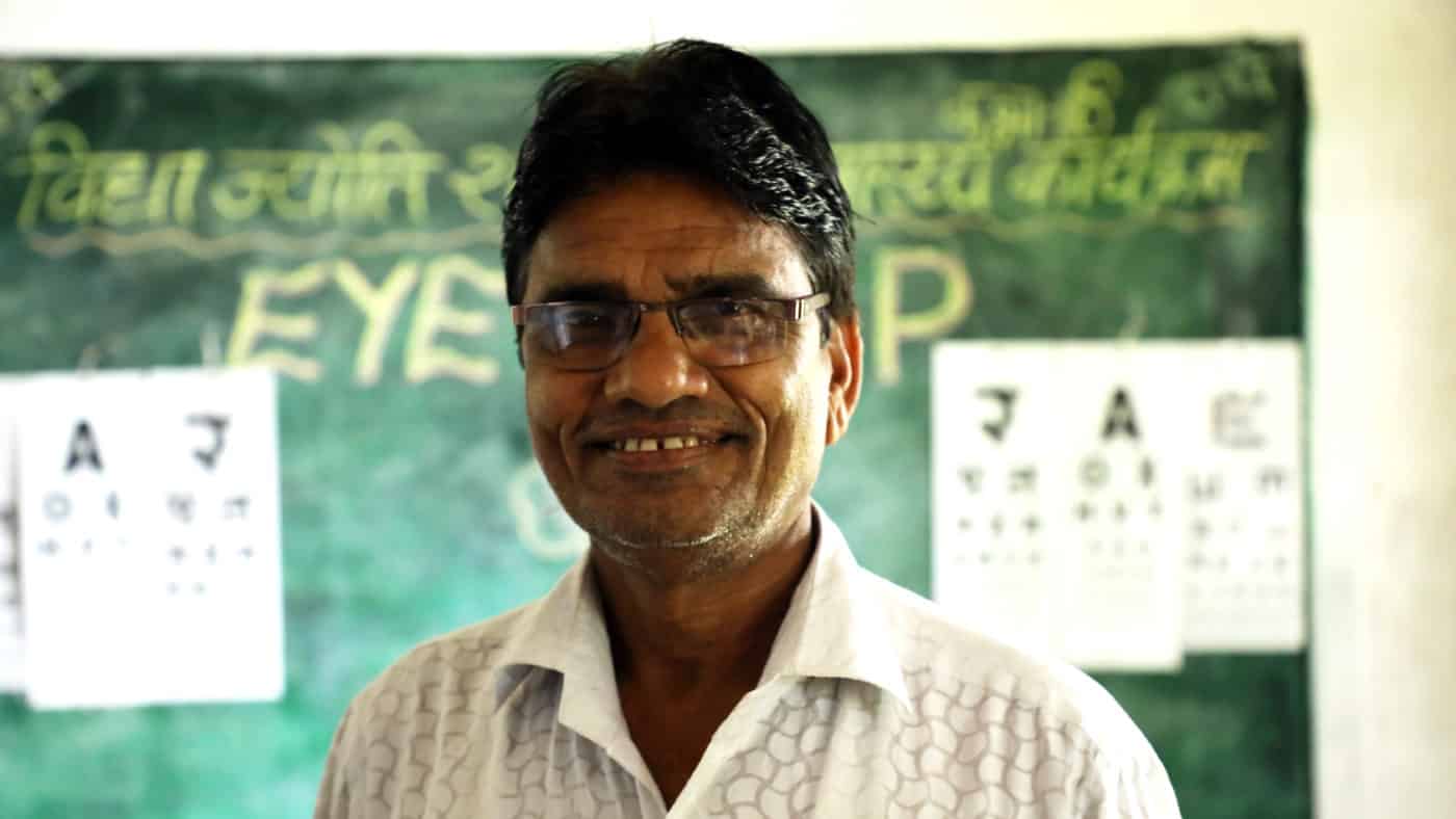 A man standing in front of a blackboard smiling.