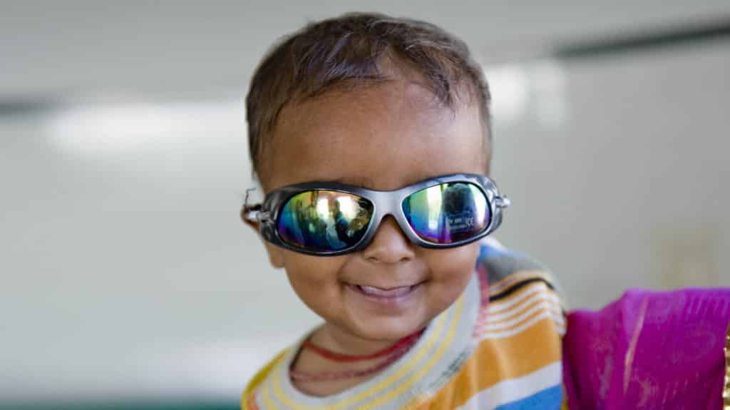 A young boy smiles while wearing glasses.