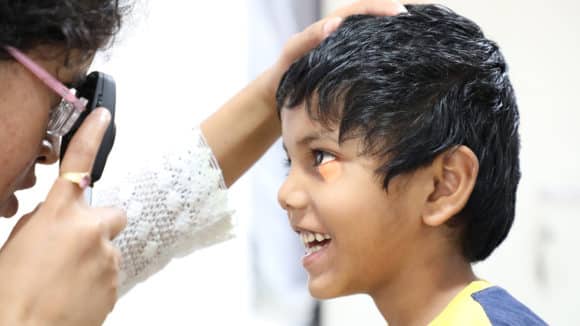 A young boy smiles while having his eyesight tested.