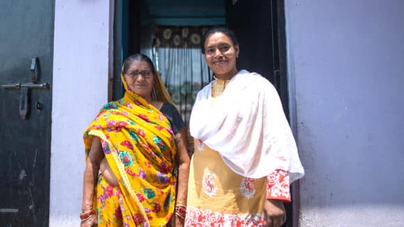 Two women stand next to each other smiling.