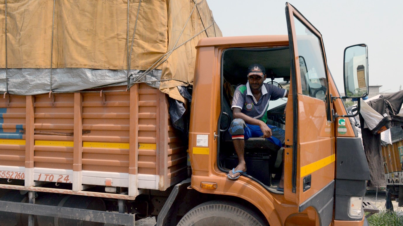 Mohammad Islam Ansari sitting in his orange truck looking out of the door.