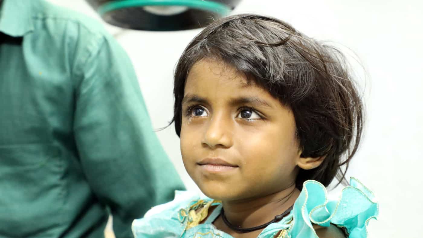 A young girl smiles after cataract surgery.