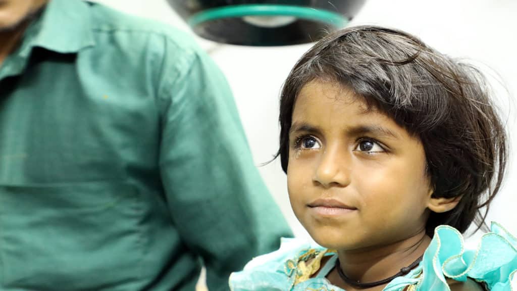 A young girl smiles after cataract surgery.