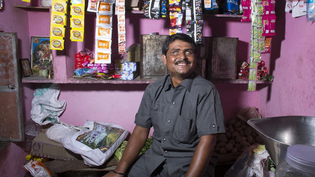 A visually impaired man sits in his shop.