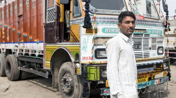 Sandeep Kumar, a truck driver from India, stands in front of his truck.