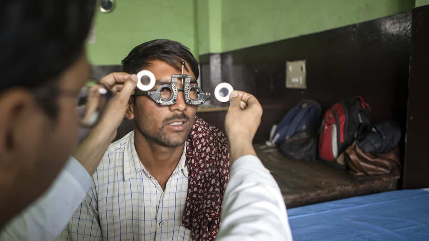 Sandeep wears special glasses while an eye health worker tests his eyes.