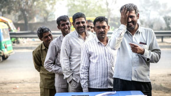 A group of men laugh while having their eye sight tested.