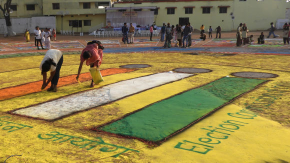 People spreading coloured sand on the floor.