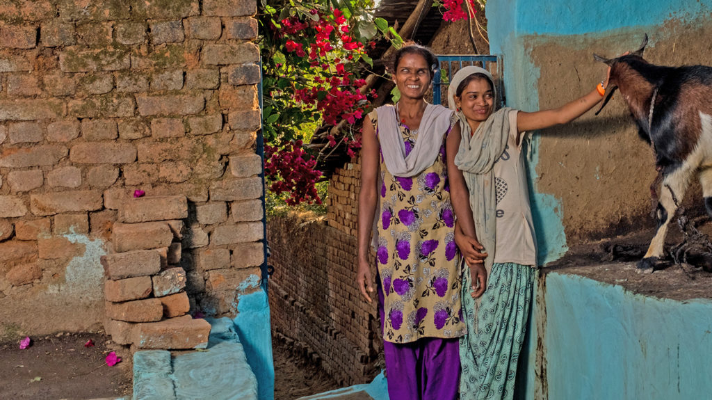 Two children stand outside smiling.