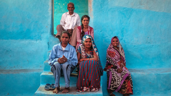 A family sit outside a house smiling.