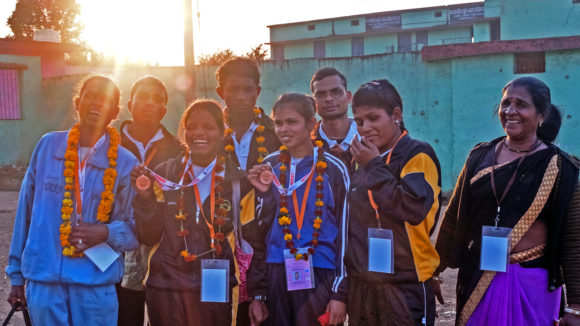 A group of female judo competitors stand together showing off their medals.